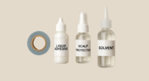 Display of common hair system accessories like a tape roll, a bottle of liquid adhesive, a scalp protector, and a solvent bottle.